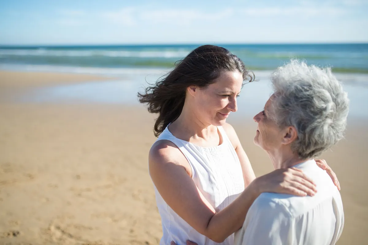 Adult daughter embracing her elderly mother outdoors